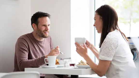 Man And Woman Sat At Table Eating